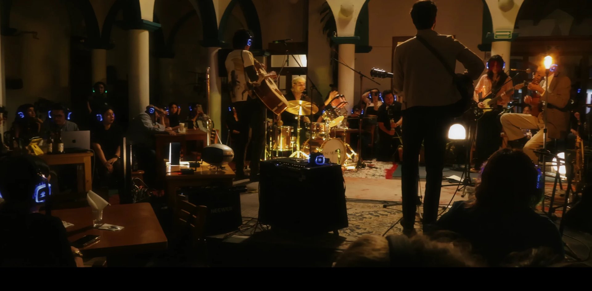 Live band performs in a historic courtyard with arched columns, audience members watching in evening lighting