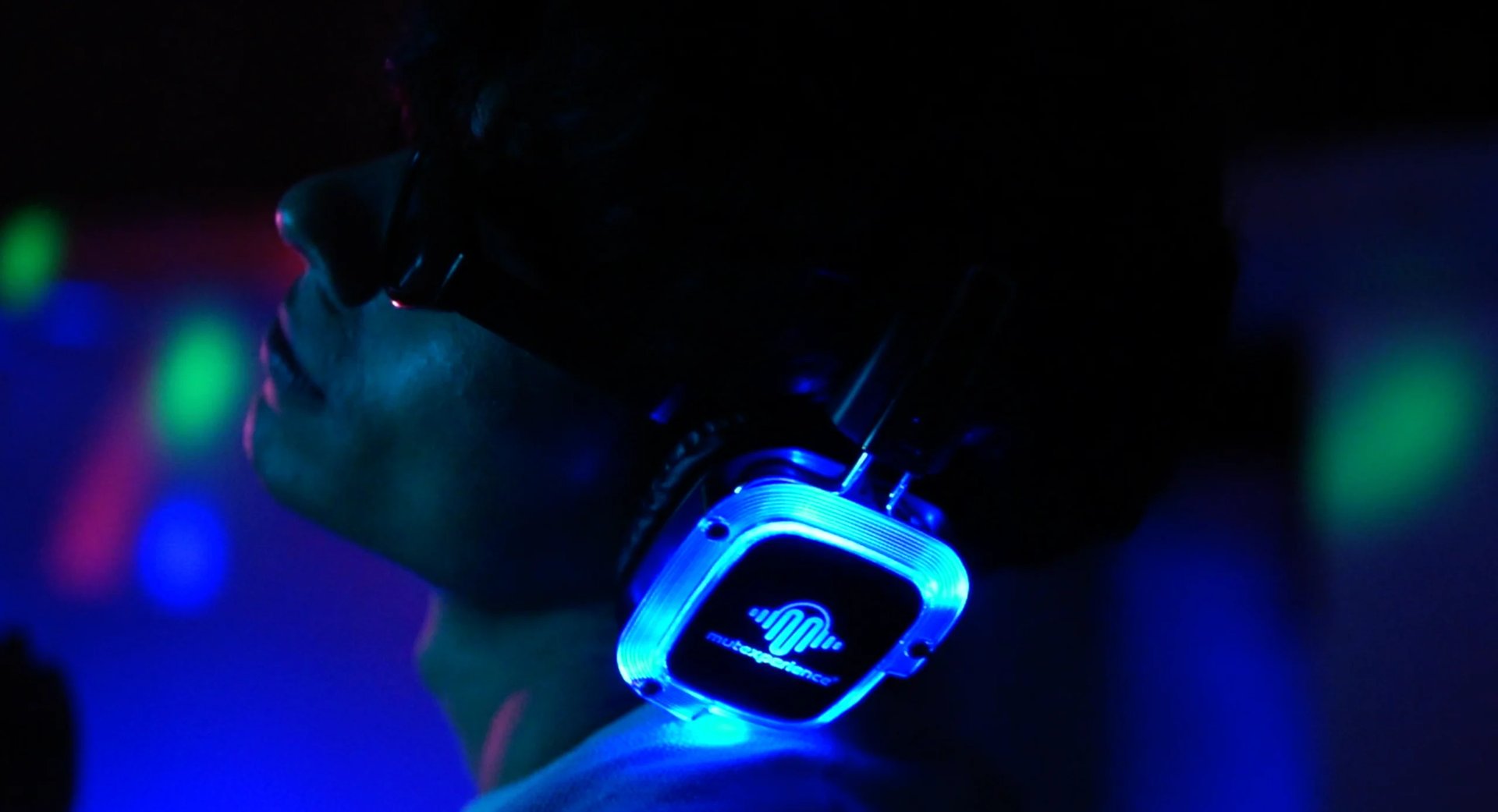 Glowing neon blue smartwatch on a wrist against dark background with colorful bokeh lights